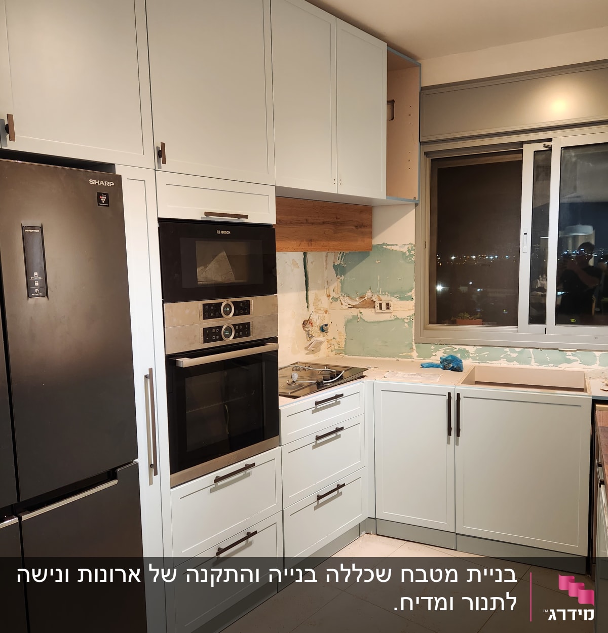 מטבח בתהליך שיפוץ עם ארונות ותנור בילט-אין